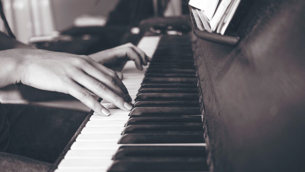 Bllack-and-white photo of a close-up on a person's hands as they are playing piano.